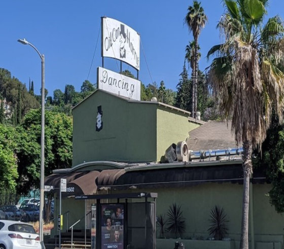 Green commercial building with roof sign reading Oil Can Harry's