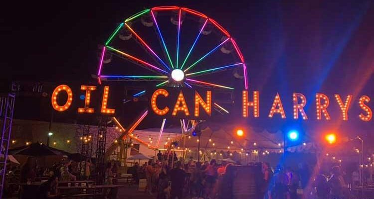 Night scene with Oil Can Harry's in neon, in front of a ferris wheel