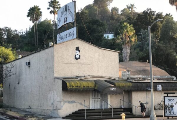 Two-story stucco building with rooftop sign.