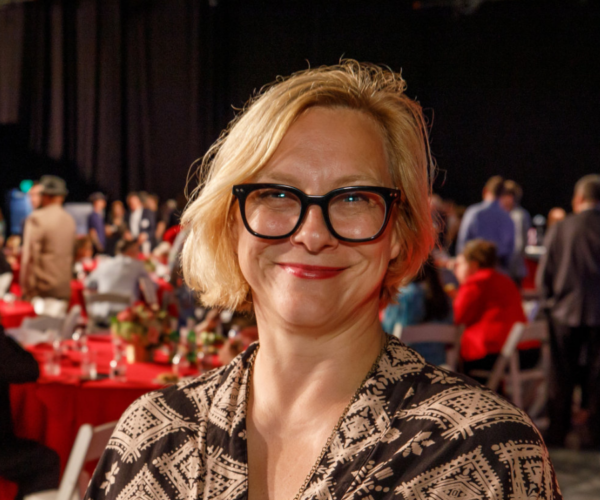 Potrait of a woman with short blonde hair and black glasses.
