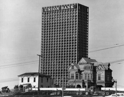 The Salt Box (left) and the Castle (right) on Bunker Hill in 1968, with the recently completed Union Bank building in the background. The homes were relocated to Heritage Square in March 1969, and destroyed by arson fire seven months later.