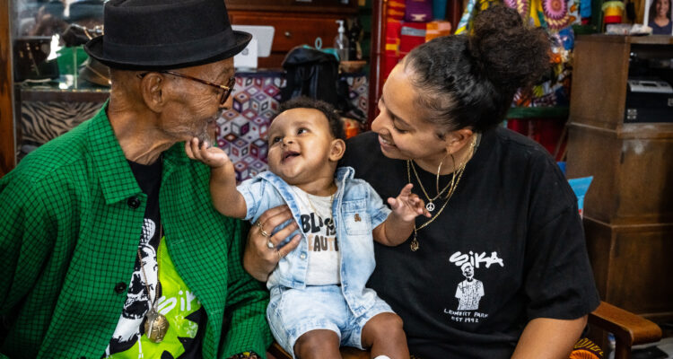 An elderly man and young women holding a baby smiling.