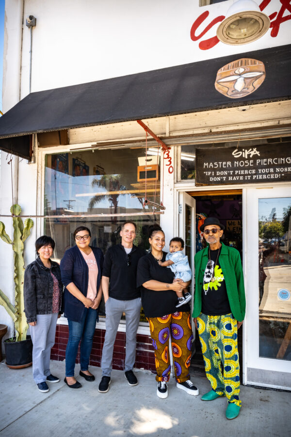 Five people posing in front of the storefront.