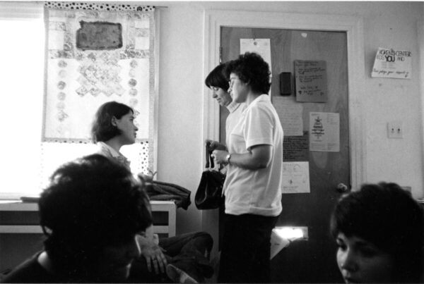 Black and white photo of three white women with short hair in conversation inside the Crenshaw Women's Center