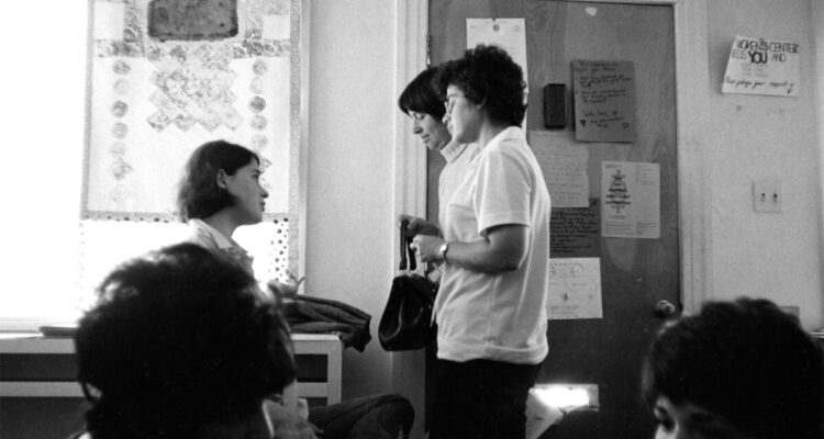 Black and white photo of three white women with short hair in conversation inside the Crenshaw Women's Center