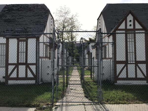 Derelict bungalow court behind chainlink fence