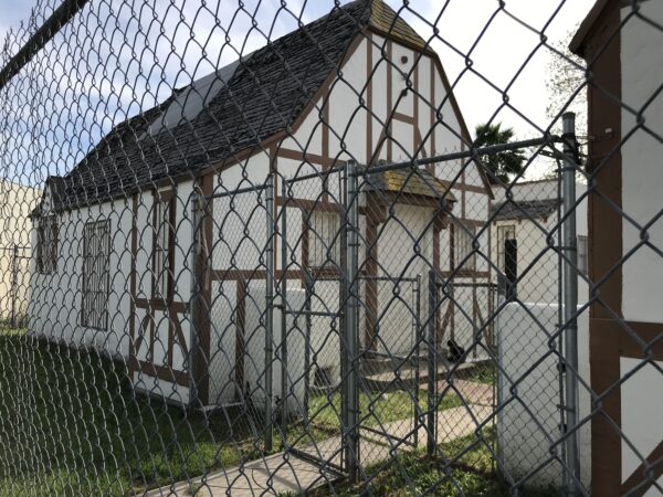 Derelict bungalow court behind chain link fence