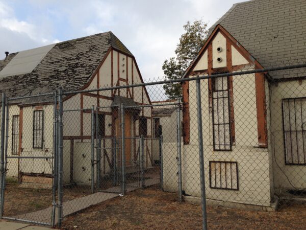 Derelict bungalow court behind chain link fence