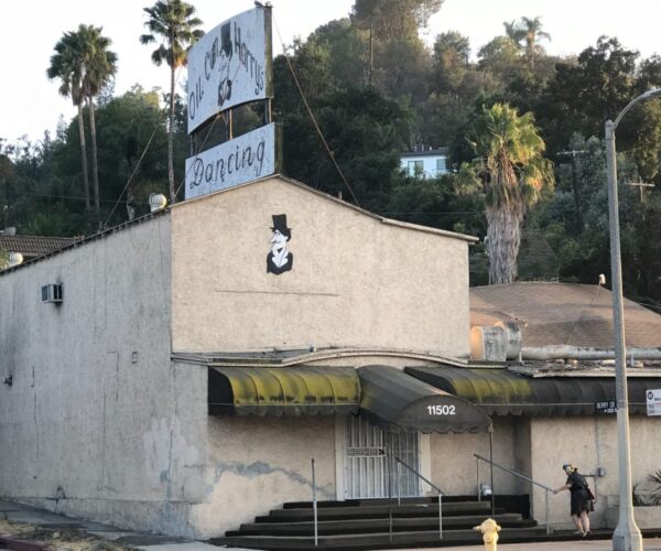 Two-story stucco building with rooftop sign.