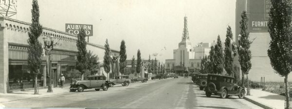 Black and white photo of car parked with Pacific theatre in the background.