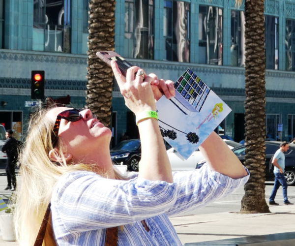 Woman takes photos with her phone along Wilshire Boulevard.