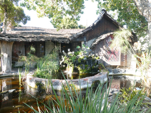 A light brown house with a pond in the front yard.