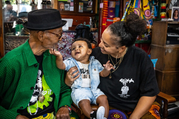 An elderly man and young women holding a baby smiling.