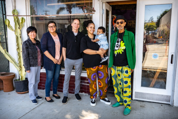 Five people posing in front of the storefront.