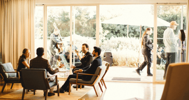 A group of people seated in chairs, engaged in conversation within a well-lit room.
