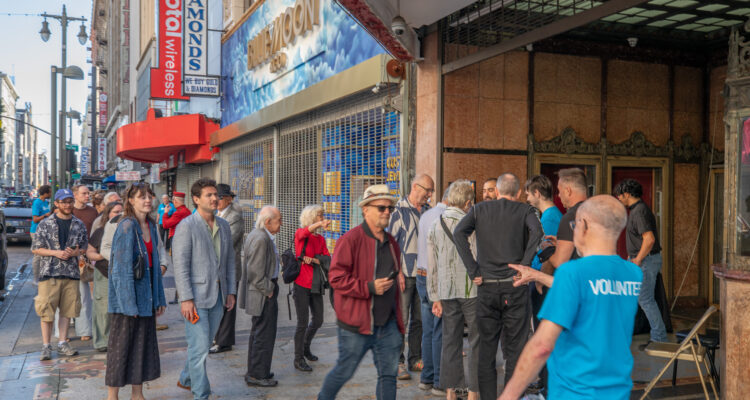 Volunteer leads guests into theatre from street